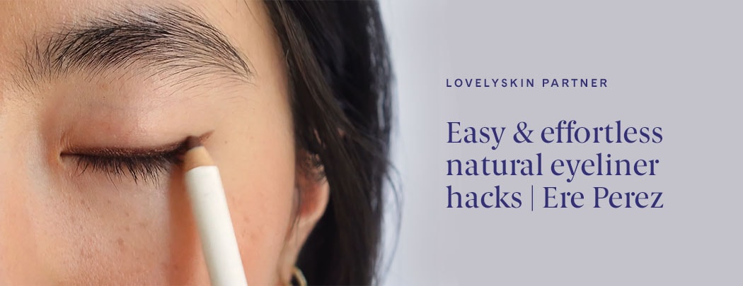 A woman with a light skin tone and dark brown hair presses a bronze eyeliner pencil to her eyelid.