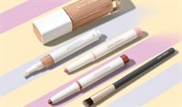 Five Jane Iredale products lay next to one another in an aesthetic line. There's a foundation, a concealer, two eyeshadow sticks, and a makeup brush.
