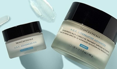 Lidded jars of SkinCeuticals A.G.E. Advanced Corrective Cream and eye cream on a light. blue background.