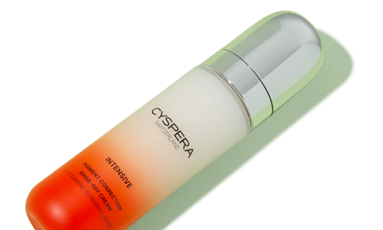 Bottle of Cyspera Intensive Pigment Correction Rinse-Off Cream on a light green background, angled diagonally