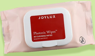 A package of Joylux Photonic Wipes™ Device Cleaning Wipes sits atop a digital illustration. The illustration is green and squiggly.