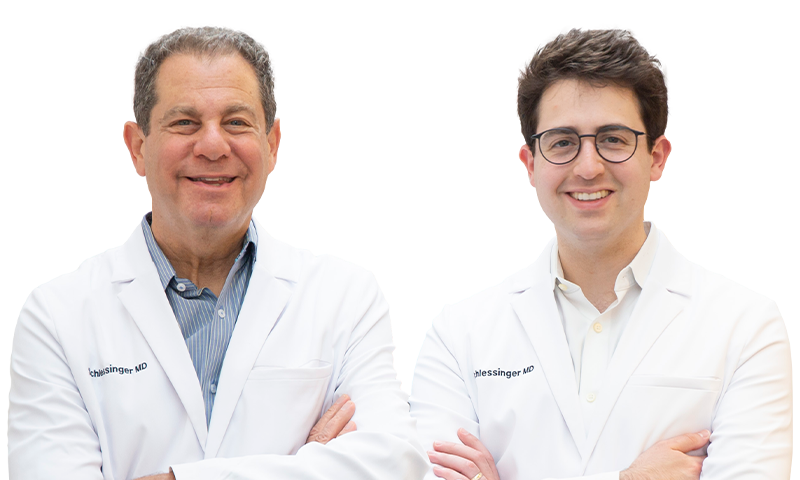 Drs. Joel and Daniel Schlessinger standing together, smiling with their arms crossed