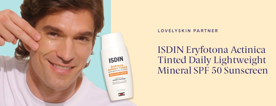 A man with a light to medium skin tone and light brown hair swatches ISDIN Eryfotona Actinica Tinted Daily Mineral SPF 50 on his cheek.
