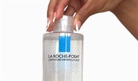 A black woman's manicured hand holds a bottle of La Roche-Posay's Micellar Water Ultra