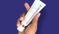 A hand holding a tube of Dermalogica skin care. How to get rid of dead skin on your face.