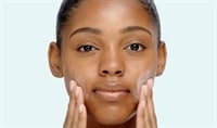 mixed race woman applies La Roche-Posay MELA B3 UV sunscreen to face with hands