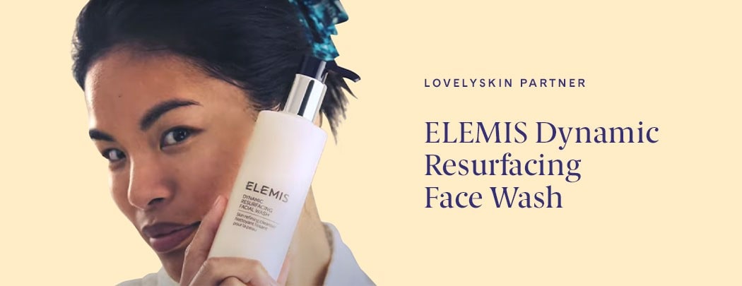 An asian woman holding a bottle of ELEMIS Dynamic Resurfacing Face Wash close to her cheek.