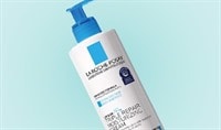 White bottle of La Roche-Posay Lipikar AP+M Triple Repair Body & Face Moisturizer For Dry Skin with a blue pump on a blue background.