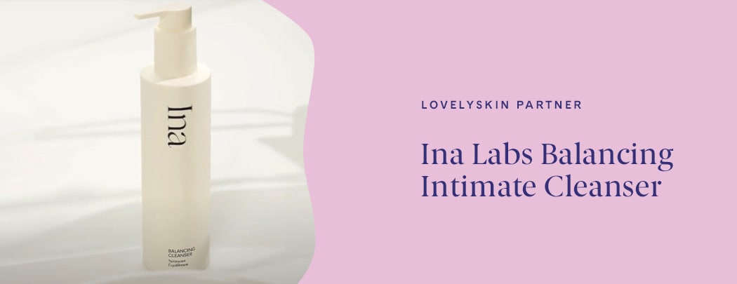 A cream colored pump bottle of Ina Balancing Cleanser sits on a white countertop with natural shadows behind it.