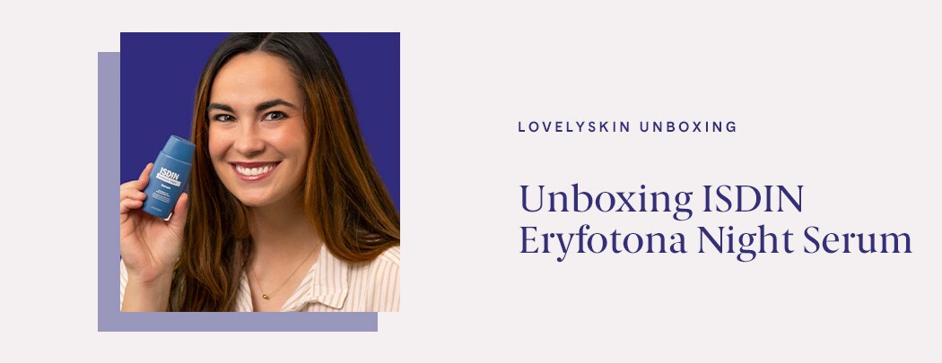 A woman with a medium skin done and dark brown hair holds a bottle of ISDIN Eryfotona Night Serum near her face while smiling.