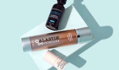 SkinCeuticals HA Intensifier Multi-Glycan Serum, ALASTIN Skincare Brightening Serum and Embryolisse eye treatment on a light blue background.