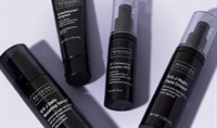 Four Revision Skincare products in black and white packaging lay on a soft purple background.