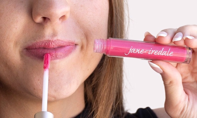 Woman smiling and applying lip gloss