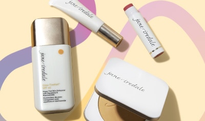 Jane Iredale PurePressed Base, Enlighten Concealer, LipDrink and Glow Fixation lay on a yellow background with a squiggle illustrated behind them.