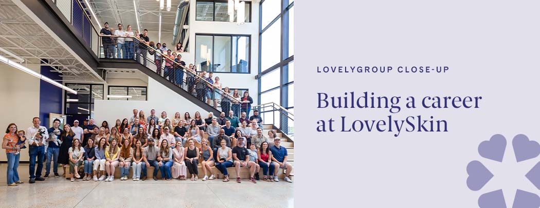 A large group of people who work at LovelySkin are gathered together in the entrance hall of the LovelyGroup headquarters. They all smile.