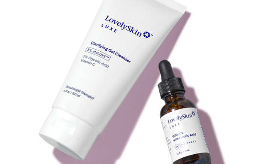 A white tube of LovelySkin LUXE Clarifying Gel Cleanser and a brown bottle with a white label of VITA-CE with Ferulic Acid laying next to one another.