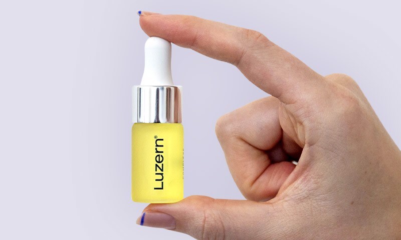 Hand holding Luzern serum bottle
