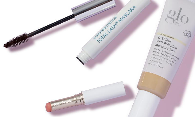 Several makeup products spread out including a mascara and lipstick on a light pink background.