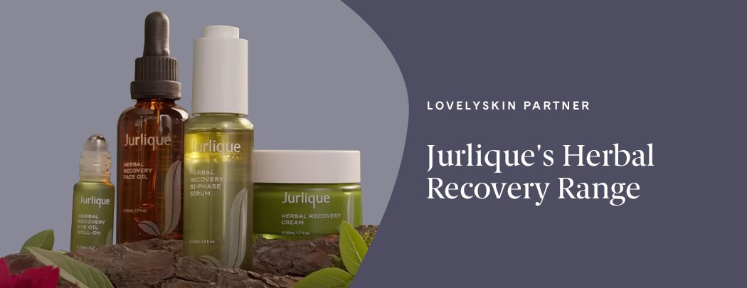 A rollerball in a green bottle, a brown bottle, a green bottle with a white dropper, and a green jar sit next to one another amongst rocks and leaves.