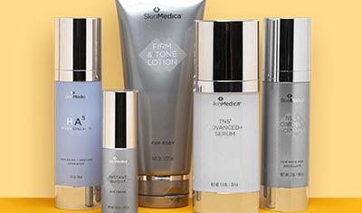 Five silver-capped containers of SkinMedica skin care products standing up against a peach. background.