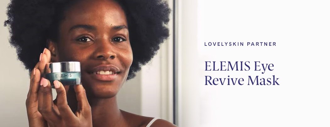 A black woman smiling softly and holding a jar of ELEMIS Eye Revive Masks in front of her cheek.