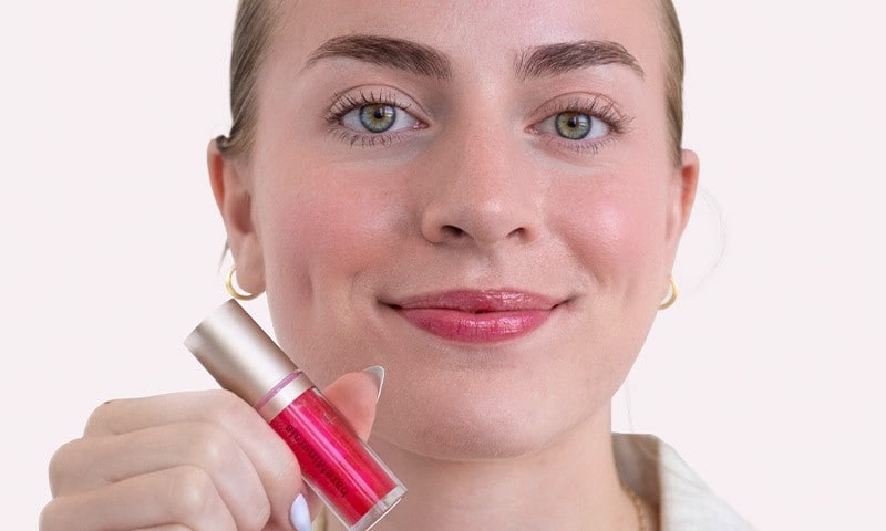 Woman smiling and holding lip oil