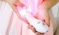 A person holds the Joylux vFit product in their hands. The red LED lights are illuminated.