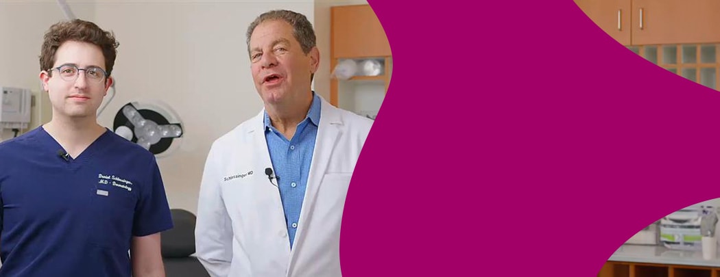 Two dermatologists stand in a clinic room next to one another.