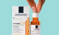 Fingers holding onto a bottle of La Roche-Posay Vitamin C12 Oil Control Serum, which is next to its packaging