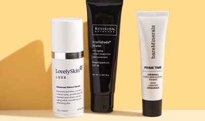 A bottle of LovelySkin LUXE retinol serum and tubes of bareMinerals and Revision Skincare primers on a gold background.