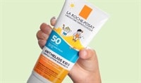 A hand with a medium skin tone holds a bottle of La Roche-Posay Anthelios Kids Gentle Lotion Sunscreen SPF 50