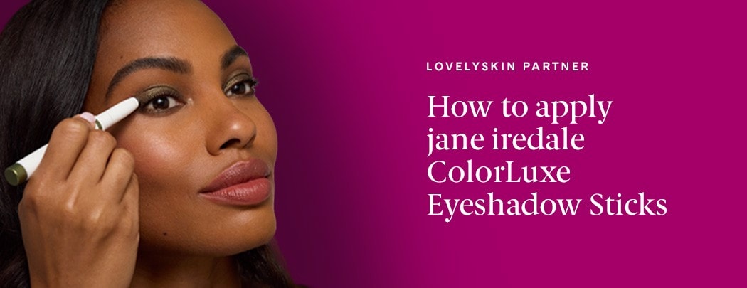 A black woman applying an eyeshadow stick to her eyelid and looking into the distance.