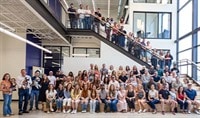 A large group of people who work at LovelySkin are gathered together in the entrance hall of the LovelyGroup headquarters. They all smile.