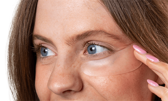 Woman applying eye patch to undereye