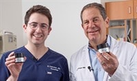 Two dermatologists, one in his 60s and one in his 30s, stand next to one another smiling as they hold SkinCeuticals P-TIOX Micro-Peptide Cream.