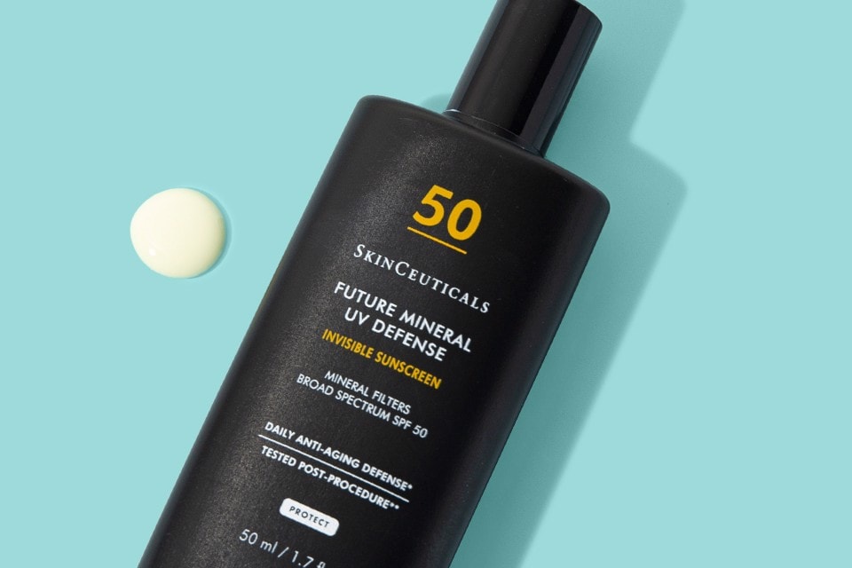SkinCeuticals Future Mineral UV Defense on a light blue background, with a small drop of sunscreen beside the bottle