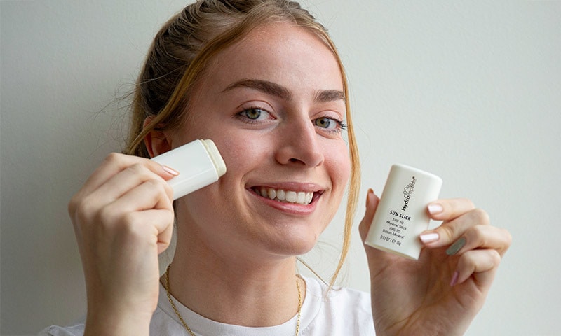 Woman using HydroPeptide Sun Slick SPF 50 Mineral Stick
