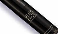 A black bottle of Veea Face Brightening Serum lays on a white background. The label on the bottle is in gold.