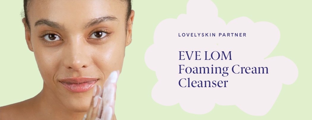 A woman with a medium skin tone rubs foaming cleanser between her palms while gazing at the camera.