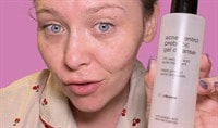 A girl with fair skin and blue eyes holds a bottle of PCA SKIN Acne Control Prebiotic Gel Cleanser.