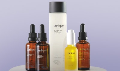 A clear bottle of clear liquid stands next to three brown bottles with black droppers and a gold bottle with a white dropper.