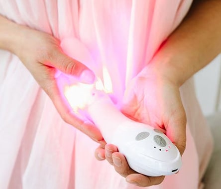 A person holds the Joylux vFit product in their hands. The red LED lights are illuminated.
