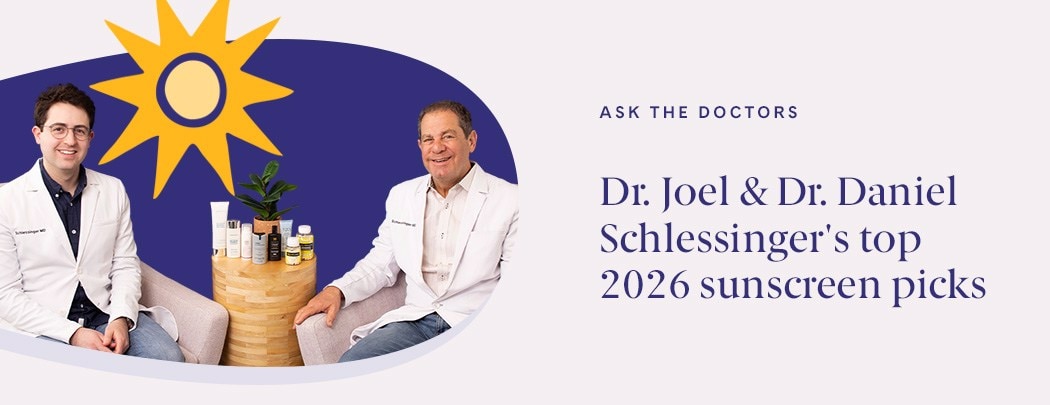 Drs. Joel and Daniel Schlessinger sit next to one another. Between them is a wood table with an array of sunscreens. They are both smiling.