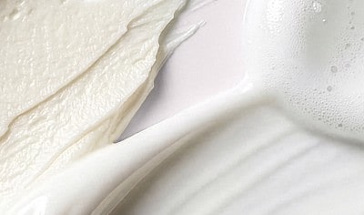 Swatches of skin care product spread across a light background, showing different textures