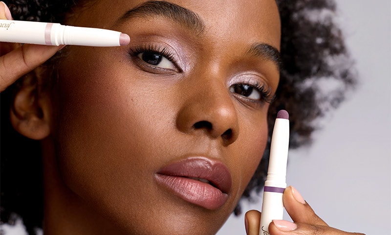 Woman applying and modeling Jane Iredale shadow sticks