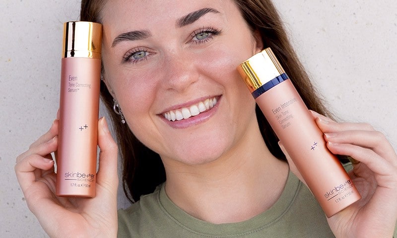 Woman holding skinbetter science Even Collection and smiling