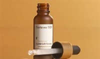 A bottle of Perricone MD Neuropeptide Eyelid Lift Serum sits on a glass top with its dropper is laid next to it. A small amount of product drips out.