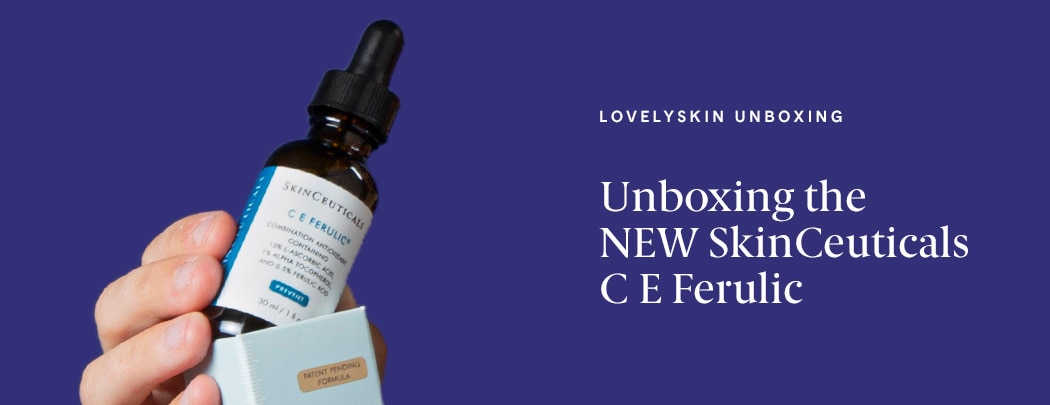 A person with an olive skin tone holds a bottle of SkinCeuticals C E Ferulic, almost as if they're pulling it out of the box.