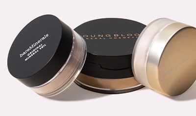 Three lidded pots of loose setting powder on an off-white background